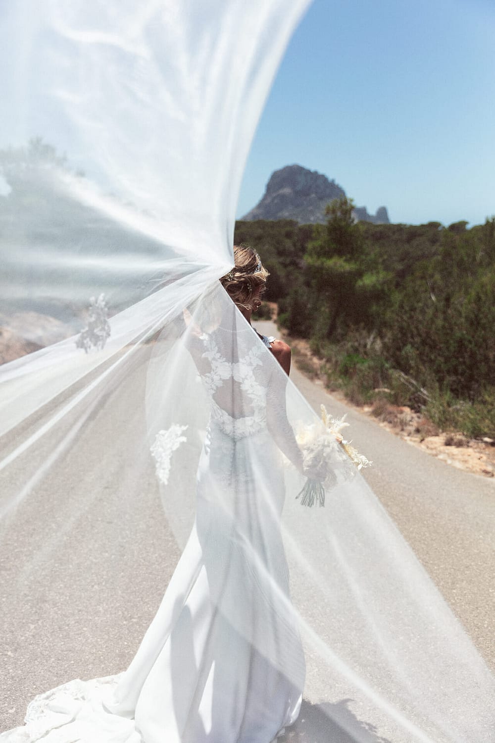 portrait of photographer in ibiza and bride playing with the veil