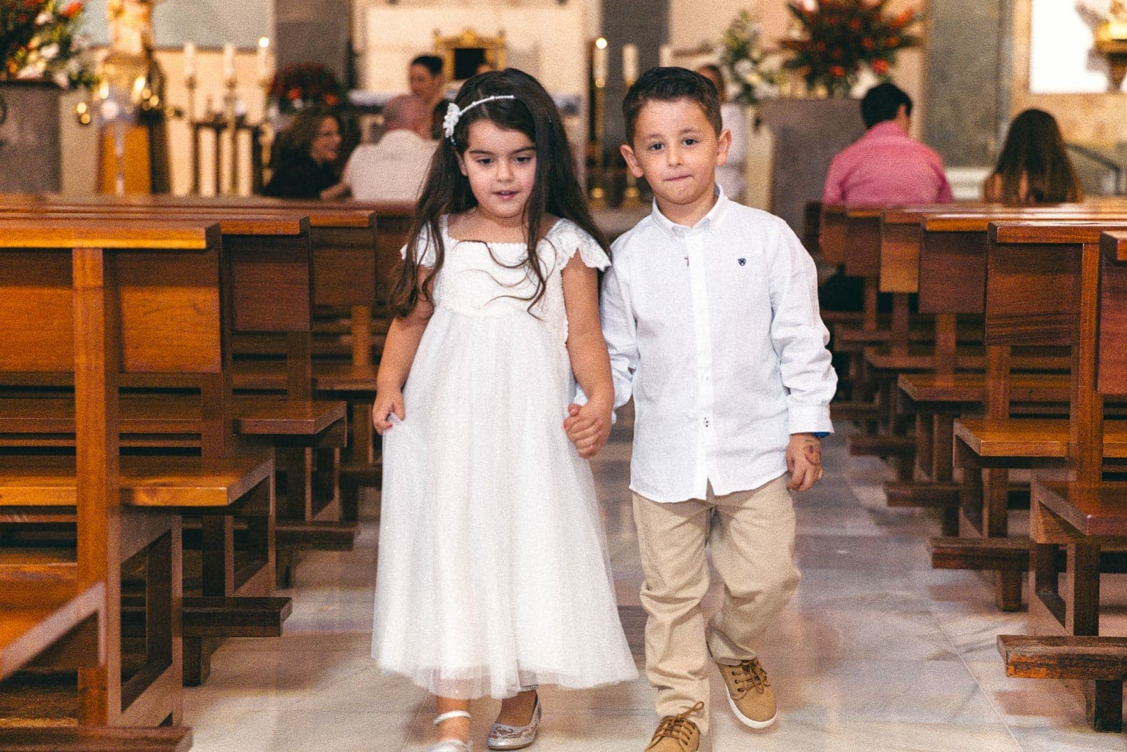 photo of two cousins holding hands and walking towards the exit of the church of san rafael