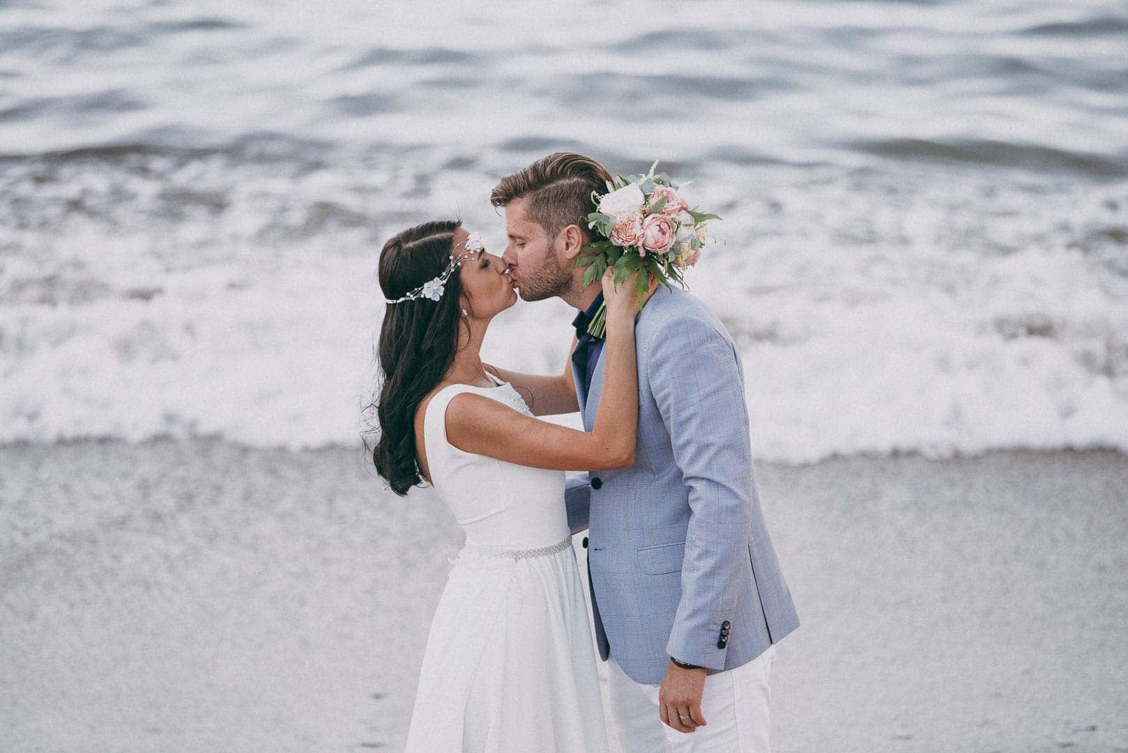 image of bride and groom kissing and posing on the shore of the port of sant miguel de ibiza