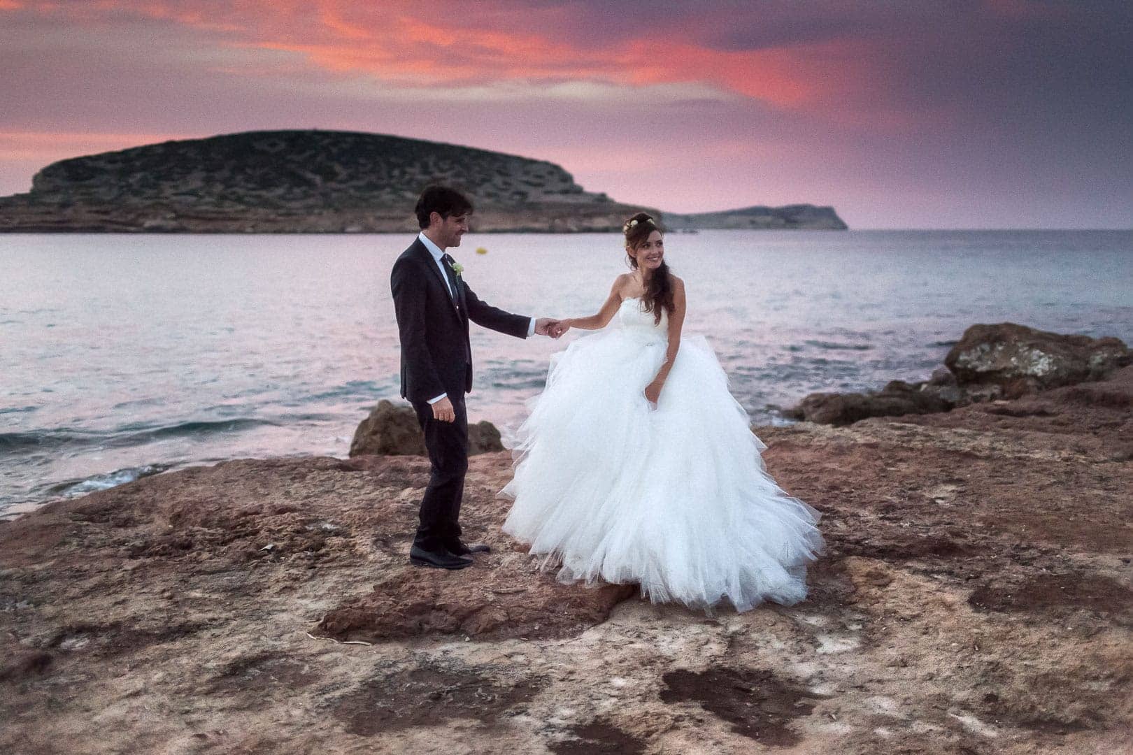 Post-wedding photography at sunset of newlyweds holding hands and happy in Cala Comte