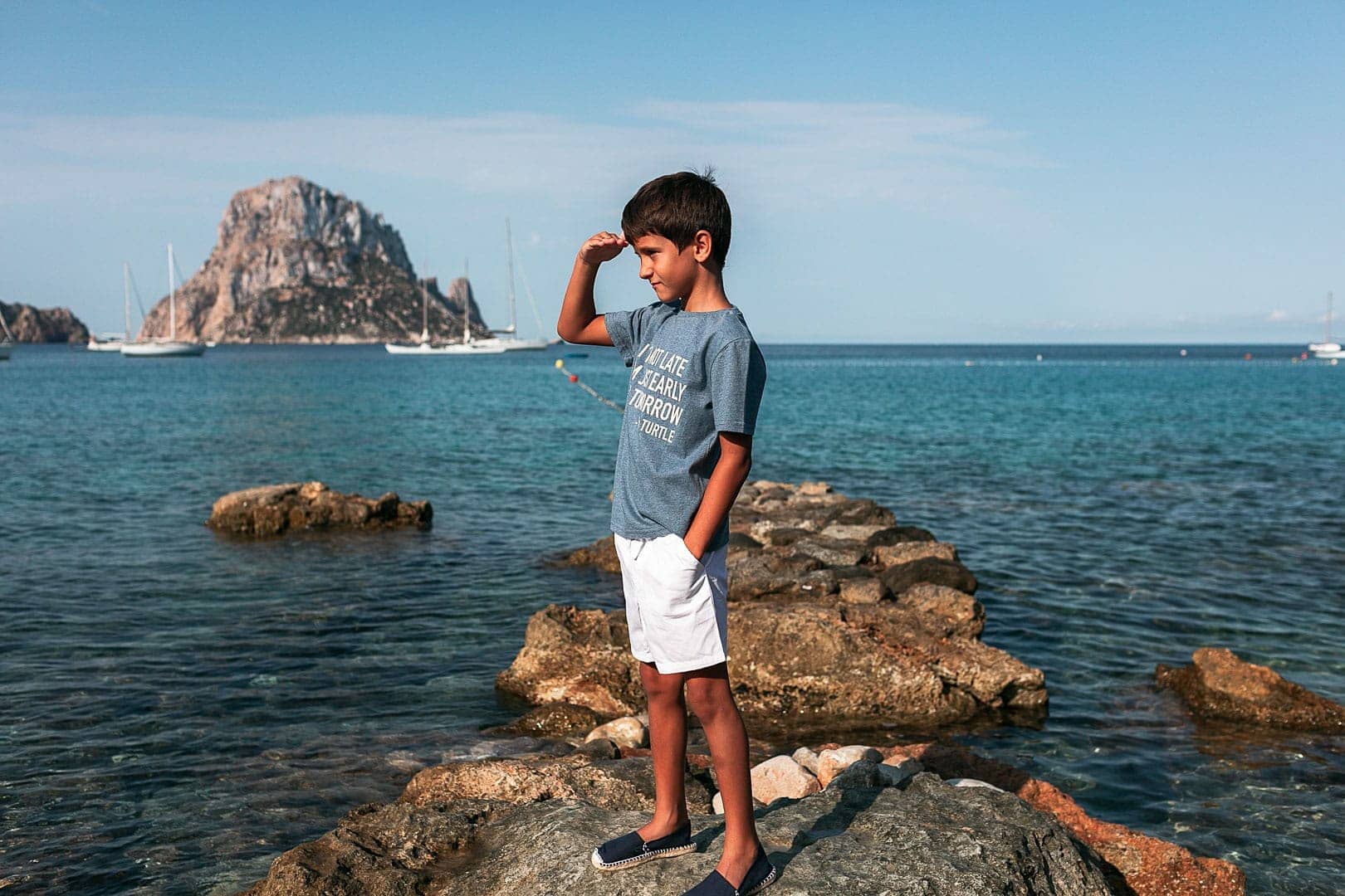 Fotografía de niño posando en las rocas de la cala de Dort por la mañana