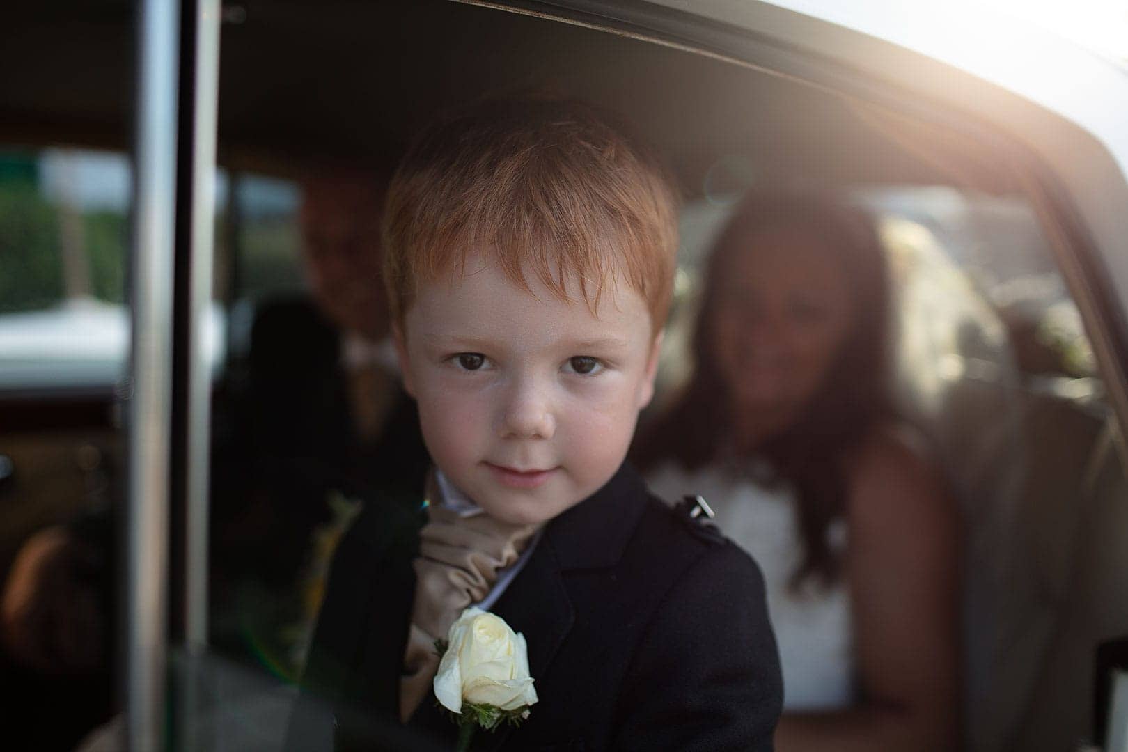 retrato fotografico de un nino mirando a la camara en el coche de los recien casados en fotógrafo de boda en Ibiza