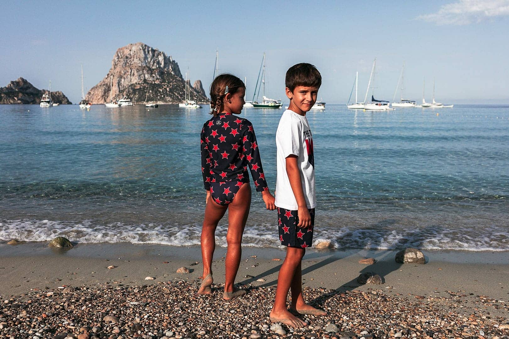 Imagen de dos niños posando en la orilla de la playa de Cala Dort de Ibiza