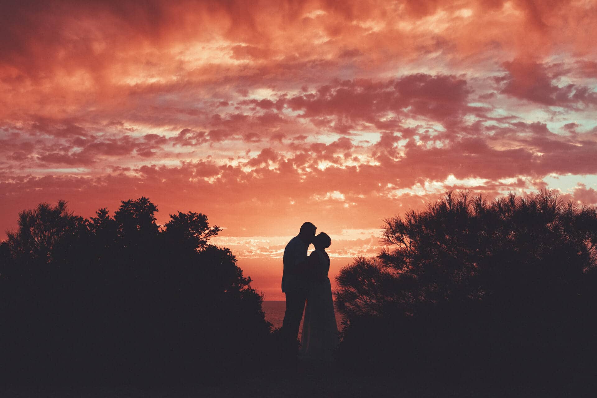 backlit image of couple kissing at sunset by photographer in ibiza