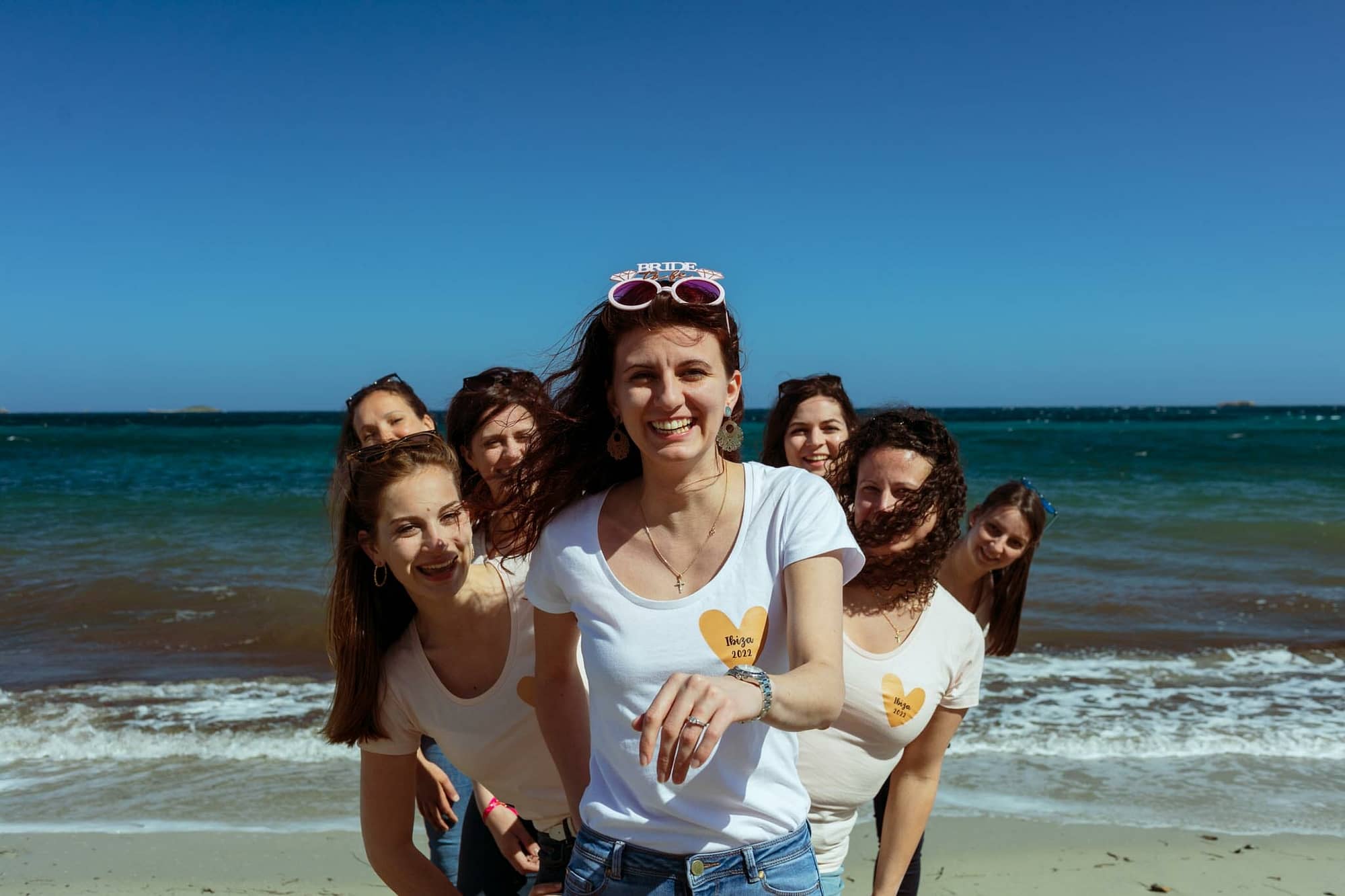 novia con amigas mostrando anillo de compromiso en la playa