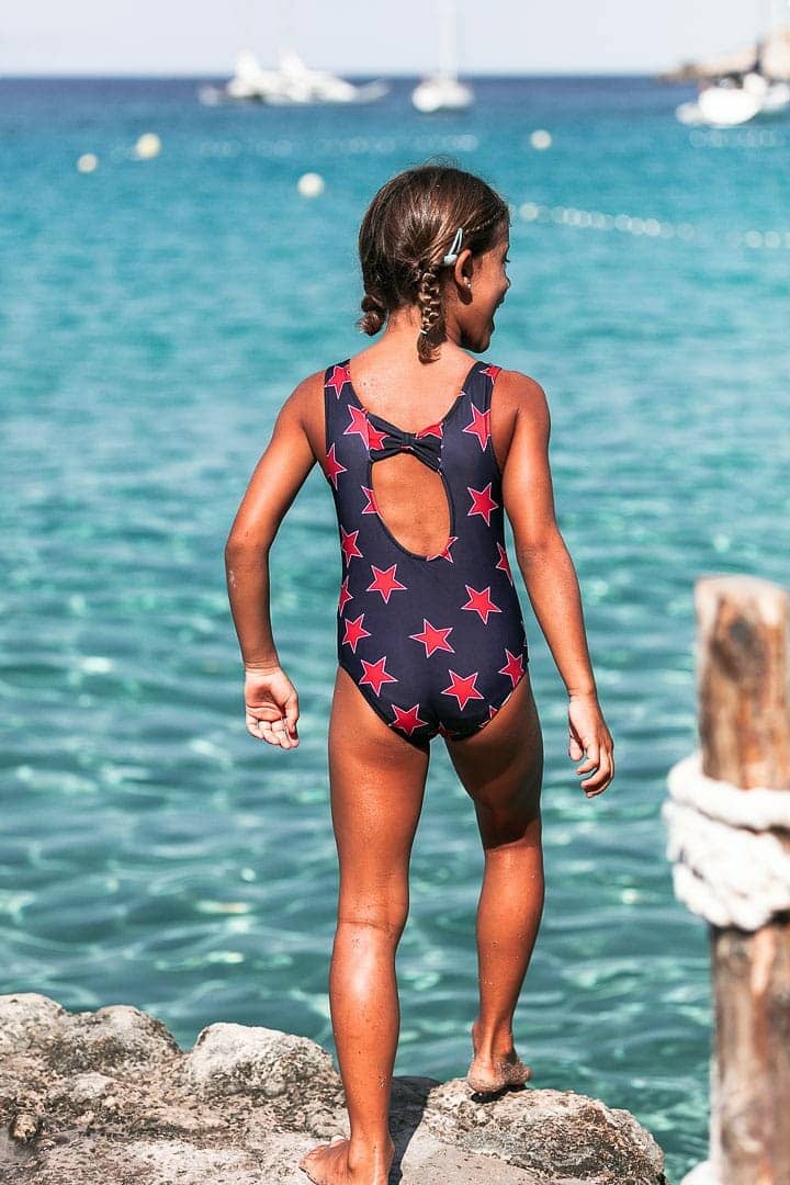 Fotografía instantanea de niña con traje de baño de marca infantil jugando en embarcadero de cala dort de Ibiza