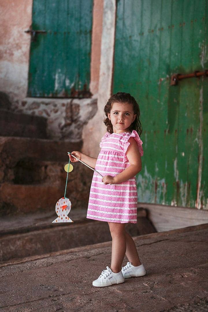 Reportaje fotográfico de ropa infantil con niña vestida con vestido rosado en embarcadero de Ibiza