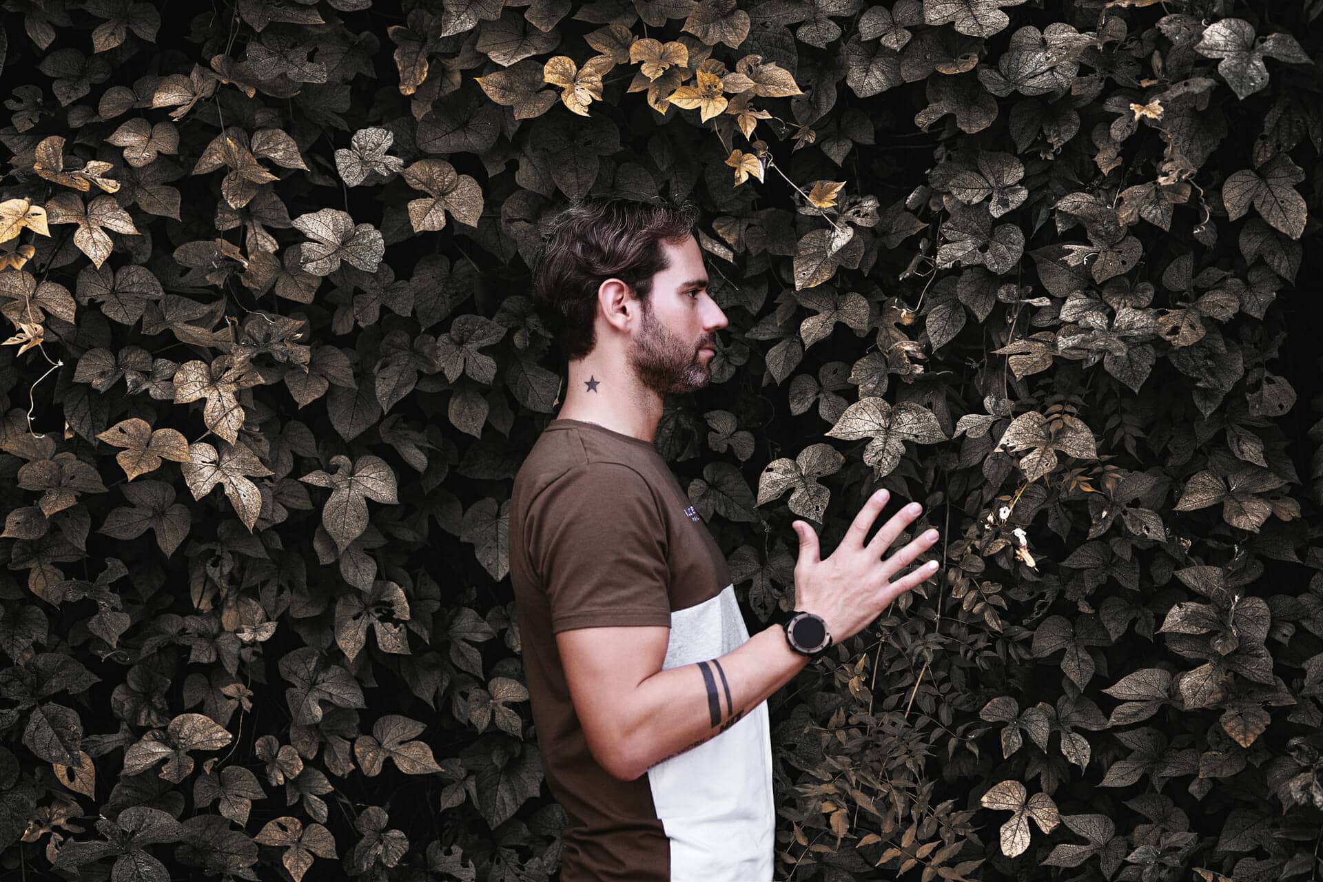 foto de joven posando detras de pared de hojas